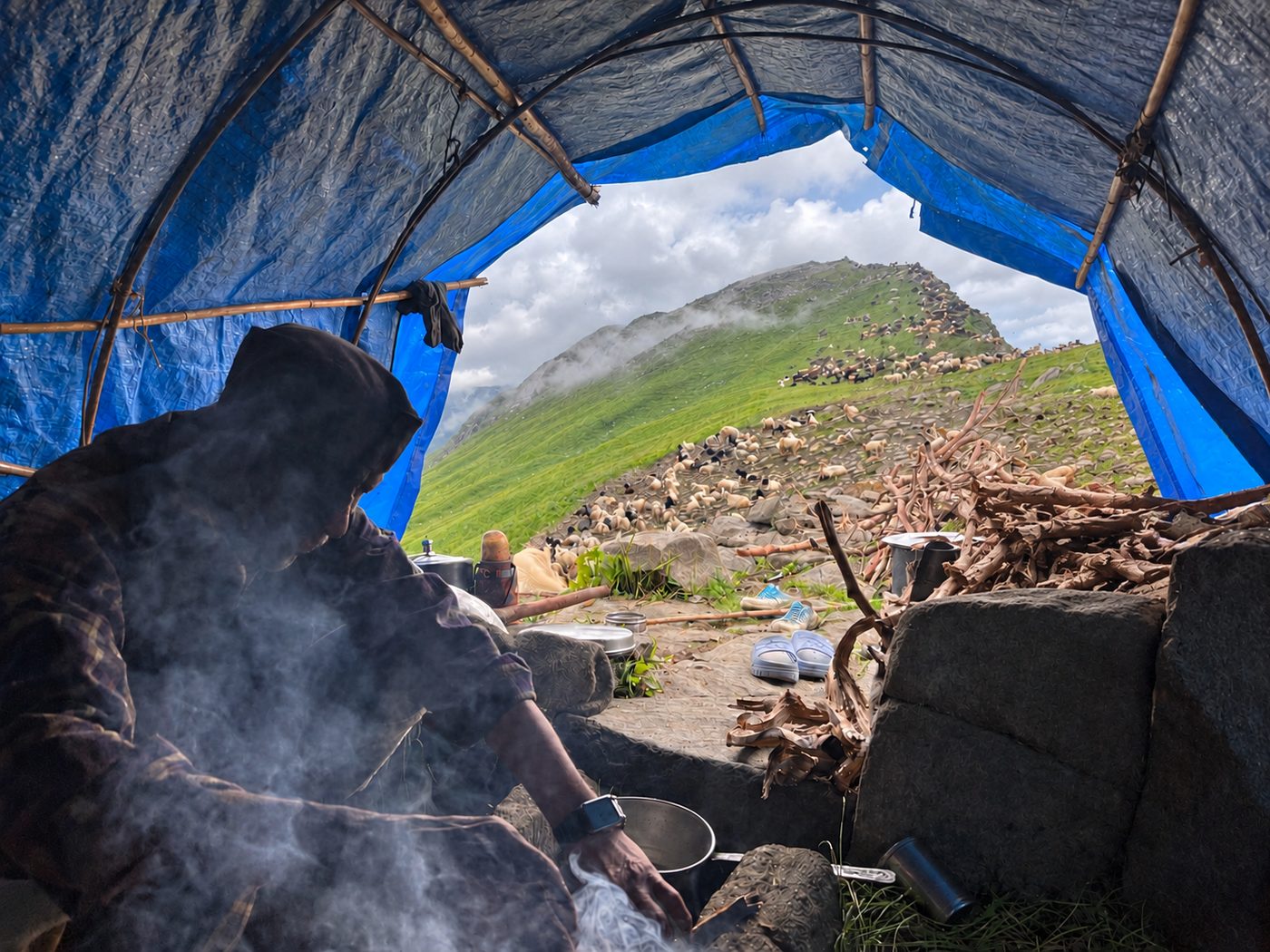 Inside a shepherd camp in the high pastures, with grazing flocks on the slope beyond