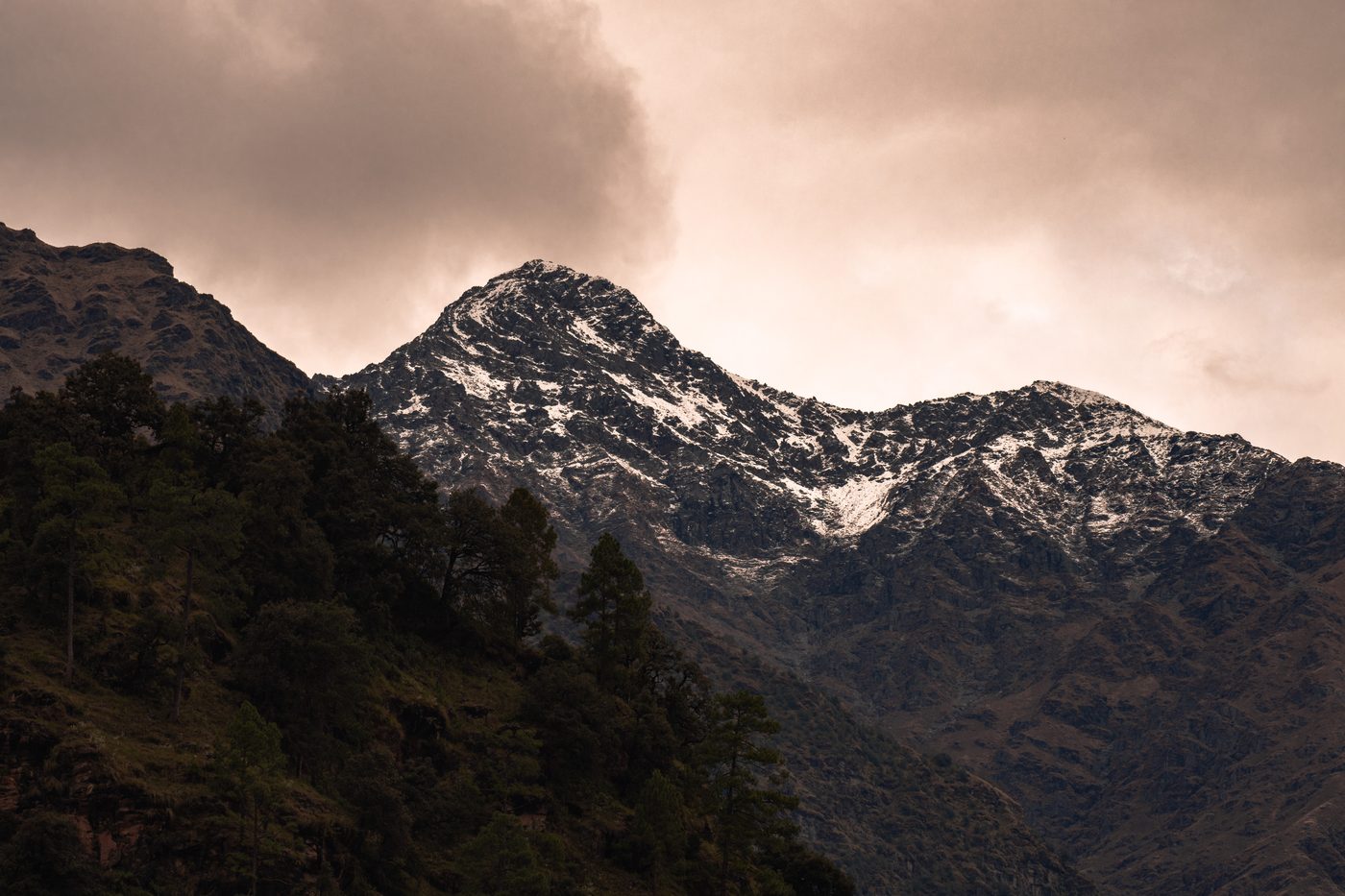 A snow-dusted Himalayan peak above forested slopes at dusk